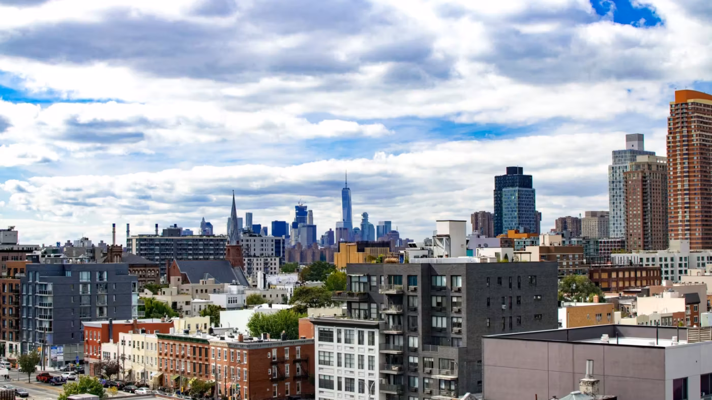 Low-rise New York blocks and rooftops with the Manhattan towers in the distance