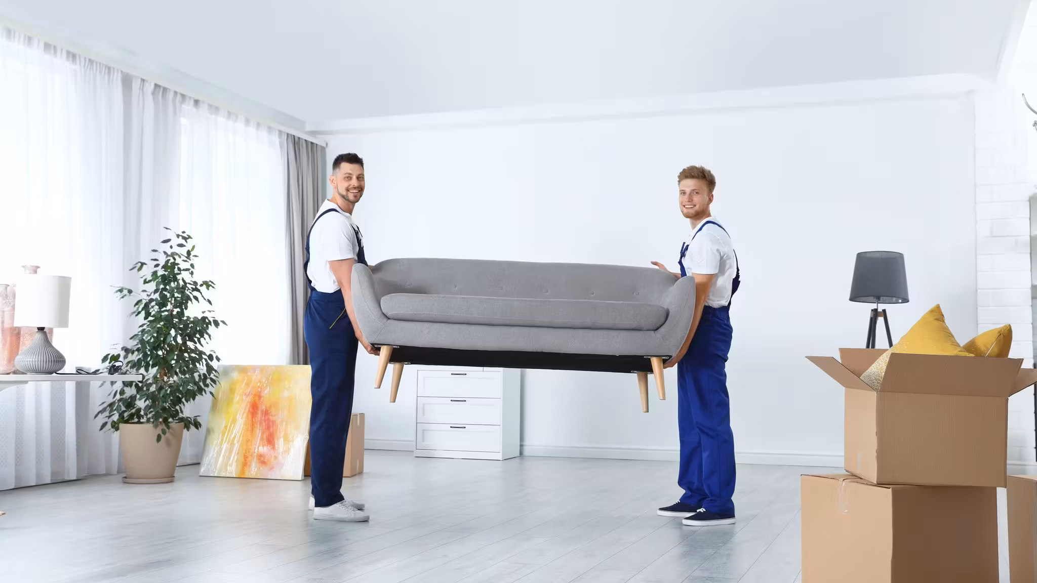 A mover carrying a bed frame across a bright empty room
