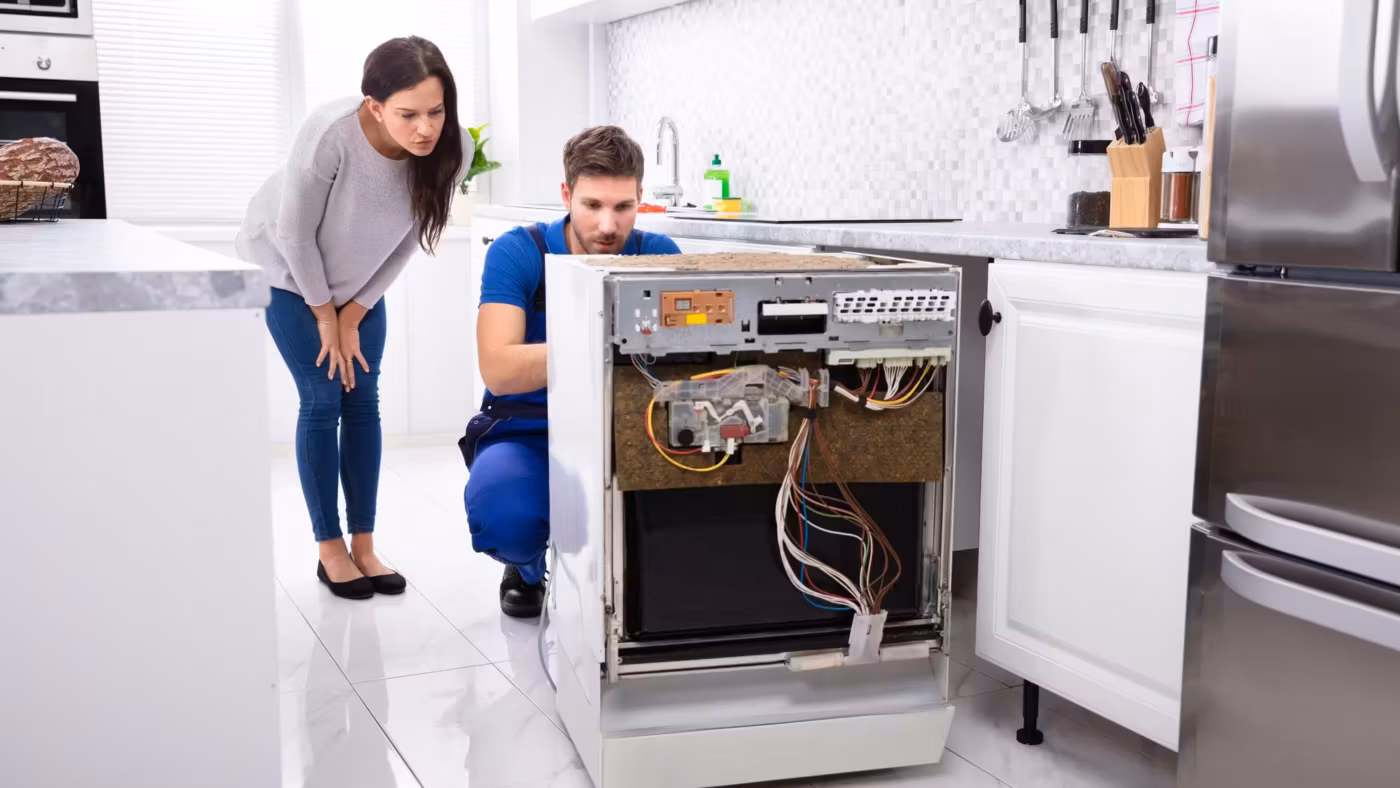 A mover working at an oven while a resident watches from beside the counter