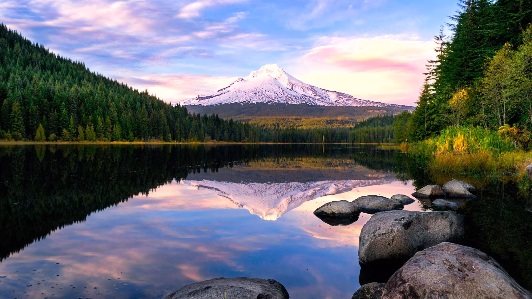 Mount Hood reflected in a still lake ringed with fir trees in Oregon