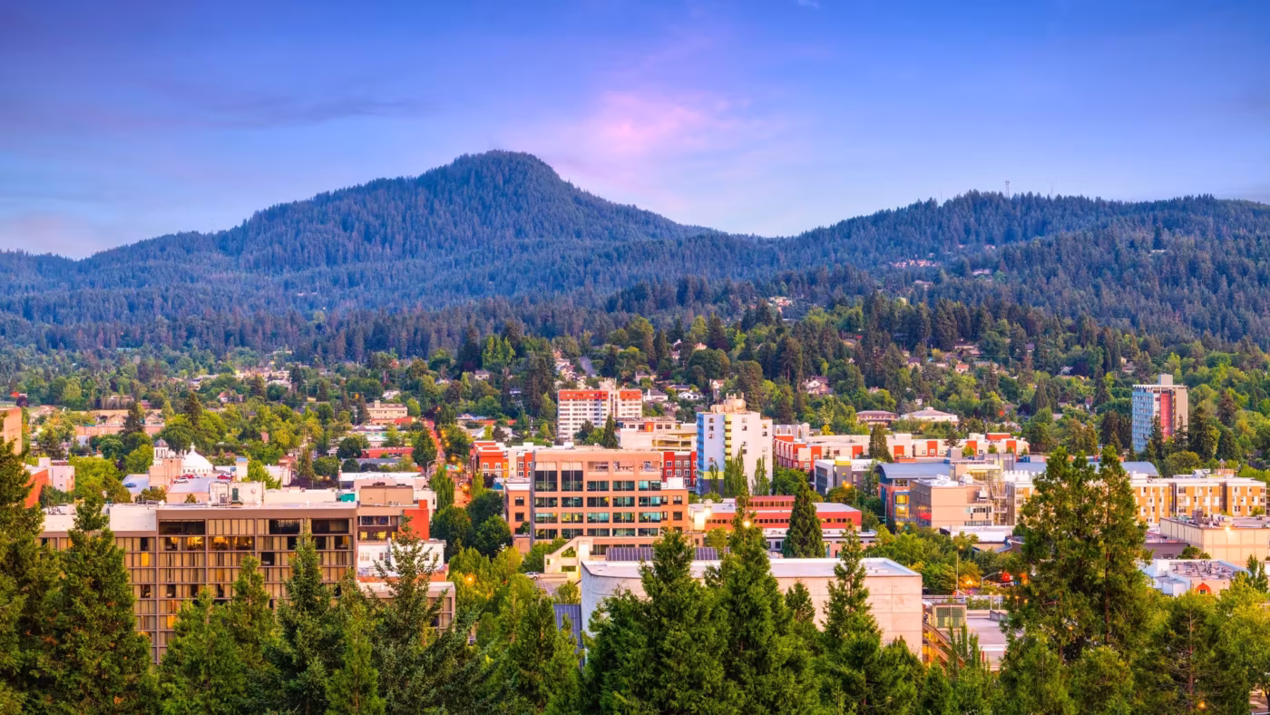 An Oregon town below a wooded butte at dusk