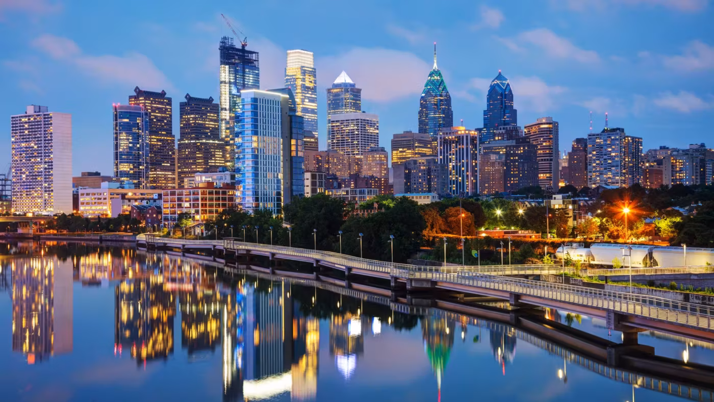 The Philadelphia skyline lit at dusk and reflected in the river