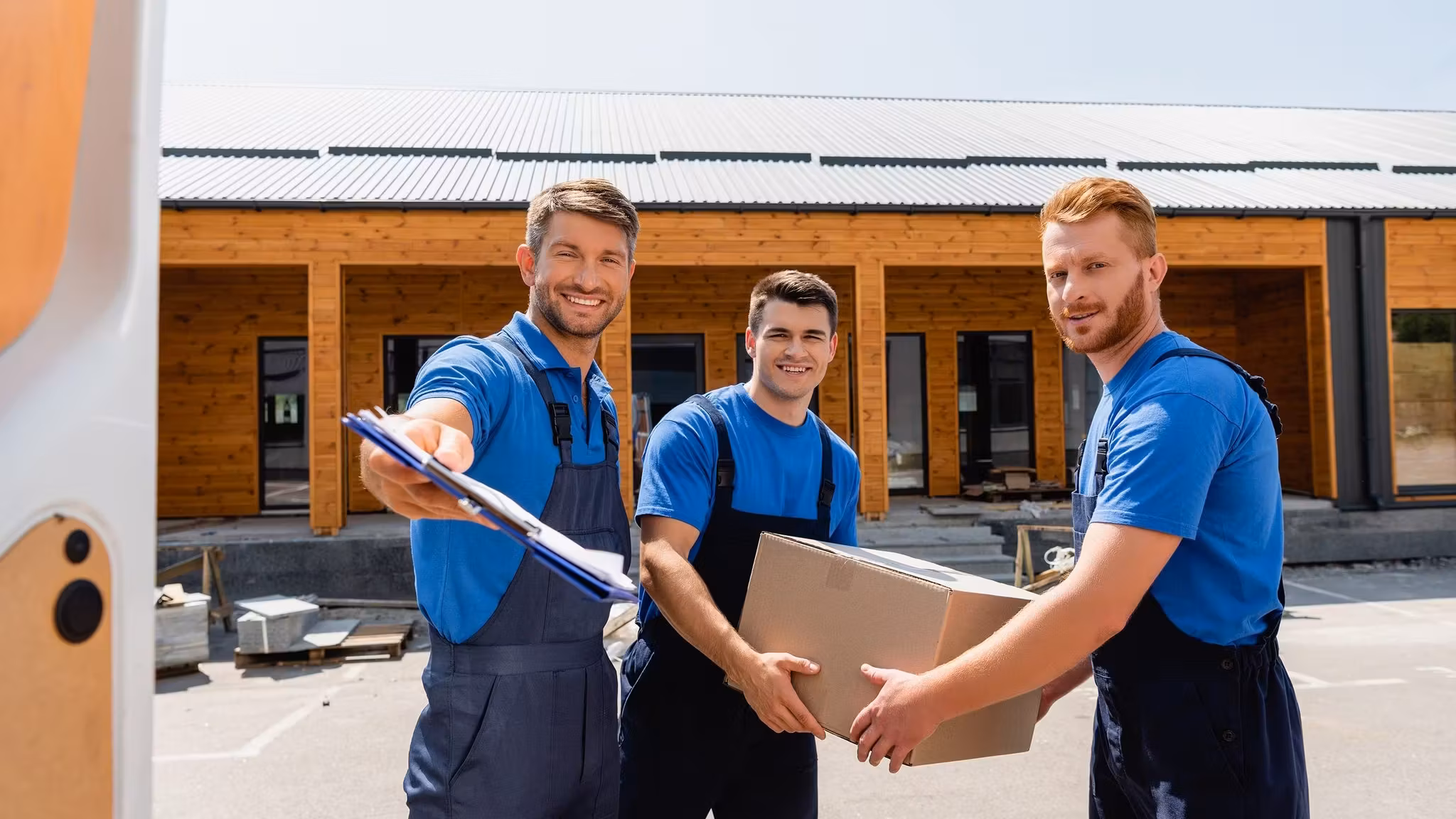 Three movers outside a building, one of them holding a clipboard