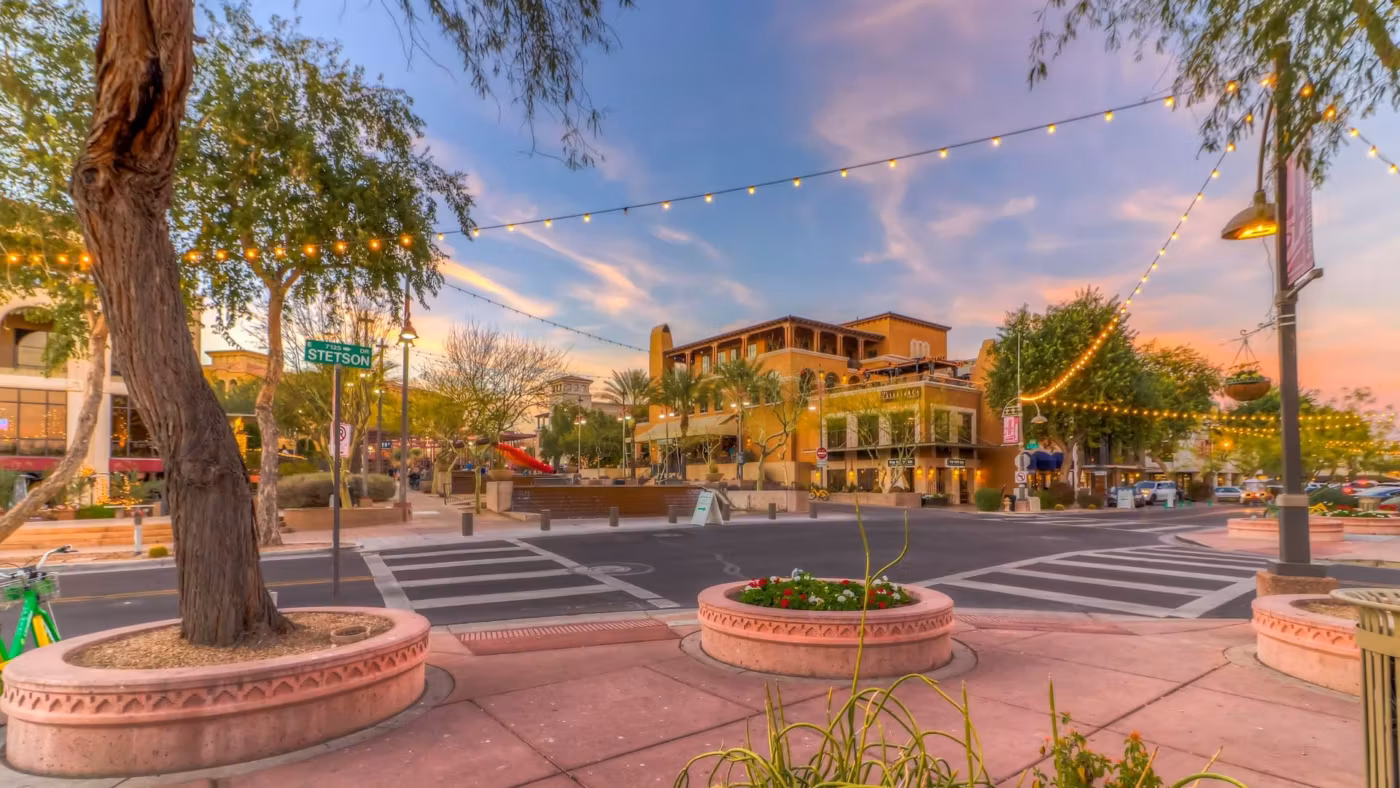 A downtown Phoenix plaza with string lights strung between the trees at dusk
