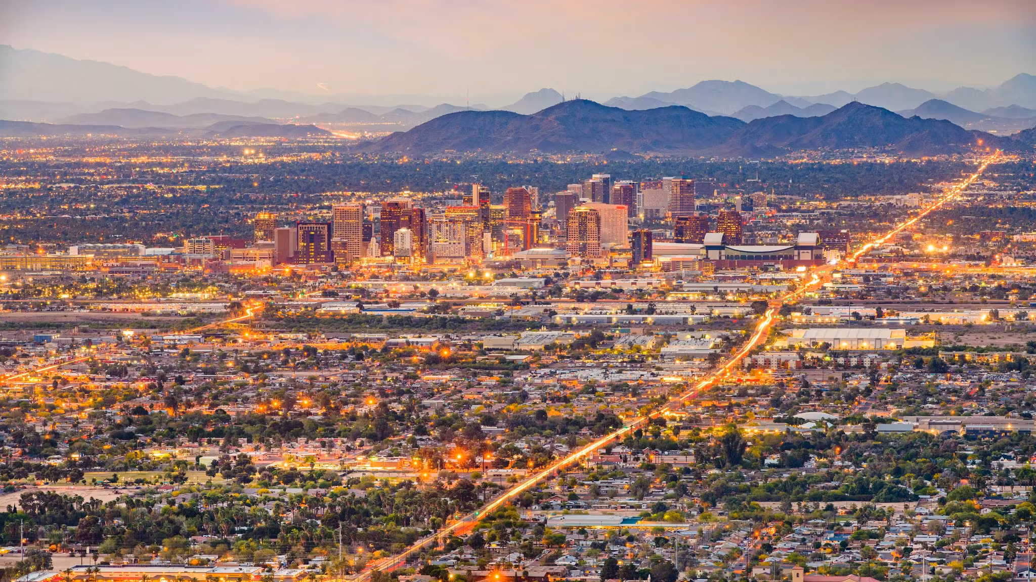 Aerial view of the Phoenix street grid at dusk with a lit arterial road running through it