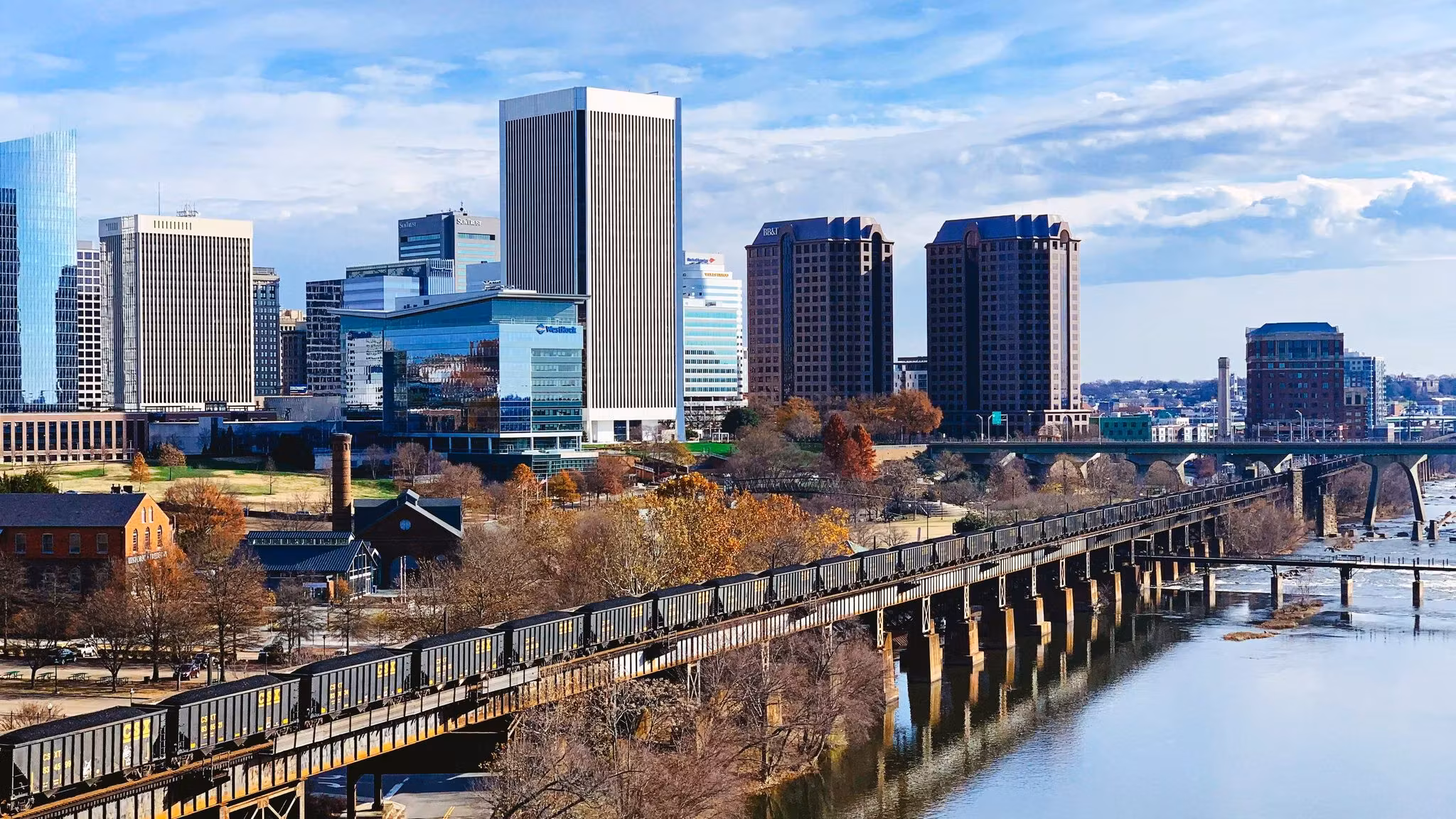 Richmond's downtown towers across the James River beside an old railway trestle in autumn