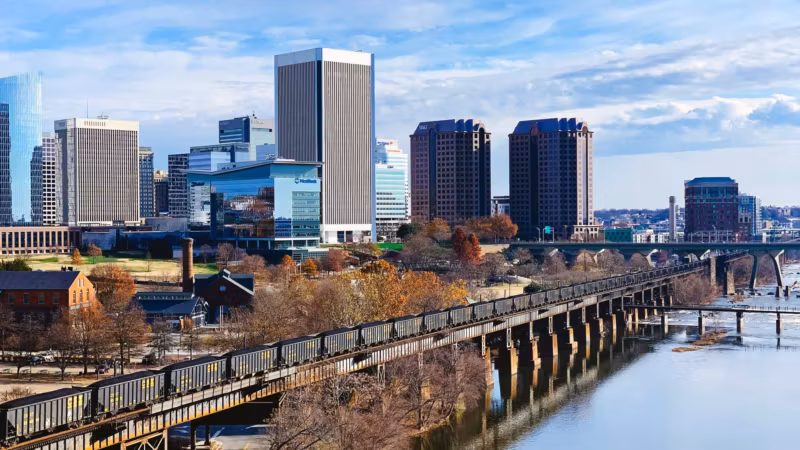 Richmond's downtown towers across the James River beside an old railway trestle in autumn