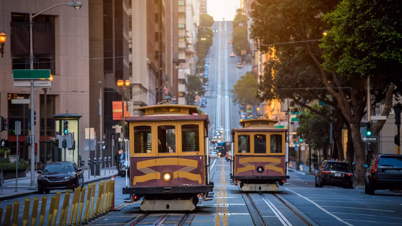 Two cable cars passing on a steep San Francisco street lined with buildings