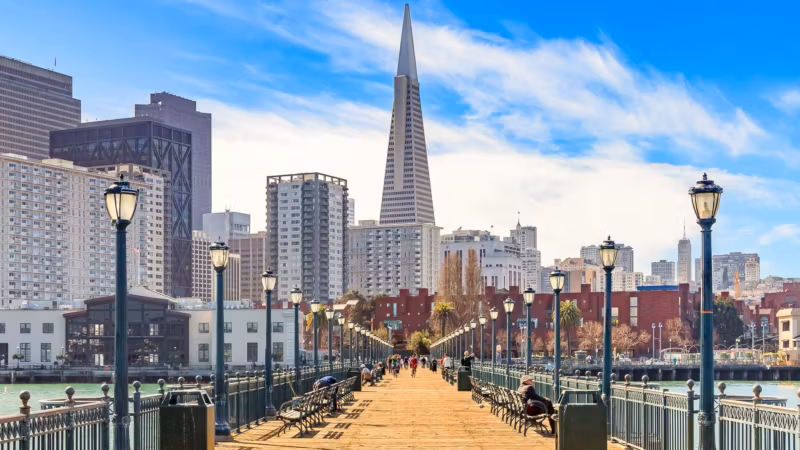 A pier promenade lined with lamp posts leading toward the Transamerica Pyramid