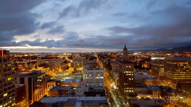 Downtown San Jose at dusk, its streets lit below a wide cloudy sky