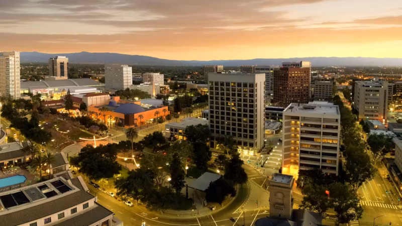 San Jose from the air at sunset, office buildings and lit roads with the hills behind