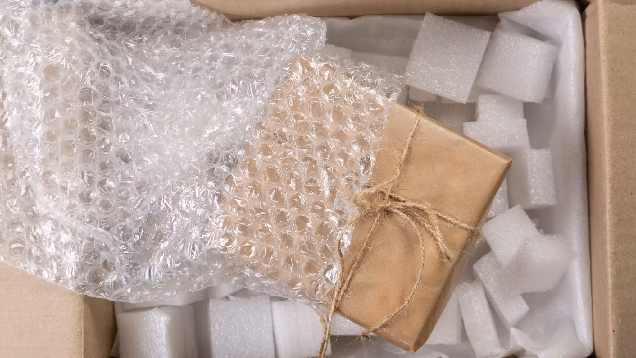 Bubble-wrapped parcels packed into a carton with foam around them
