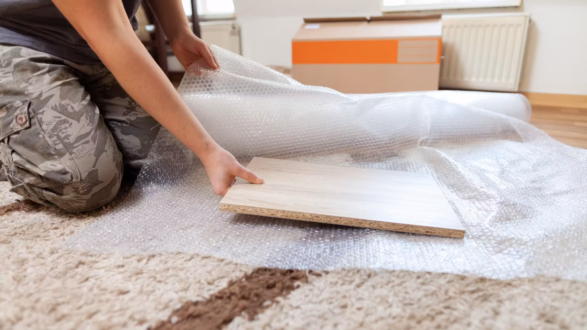A flat framed item being wrapped on a rug