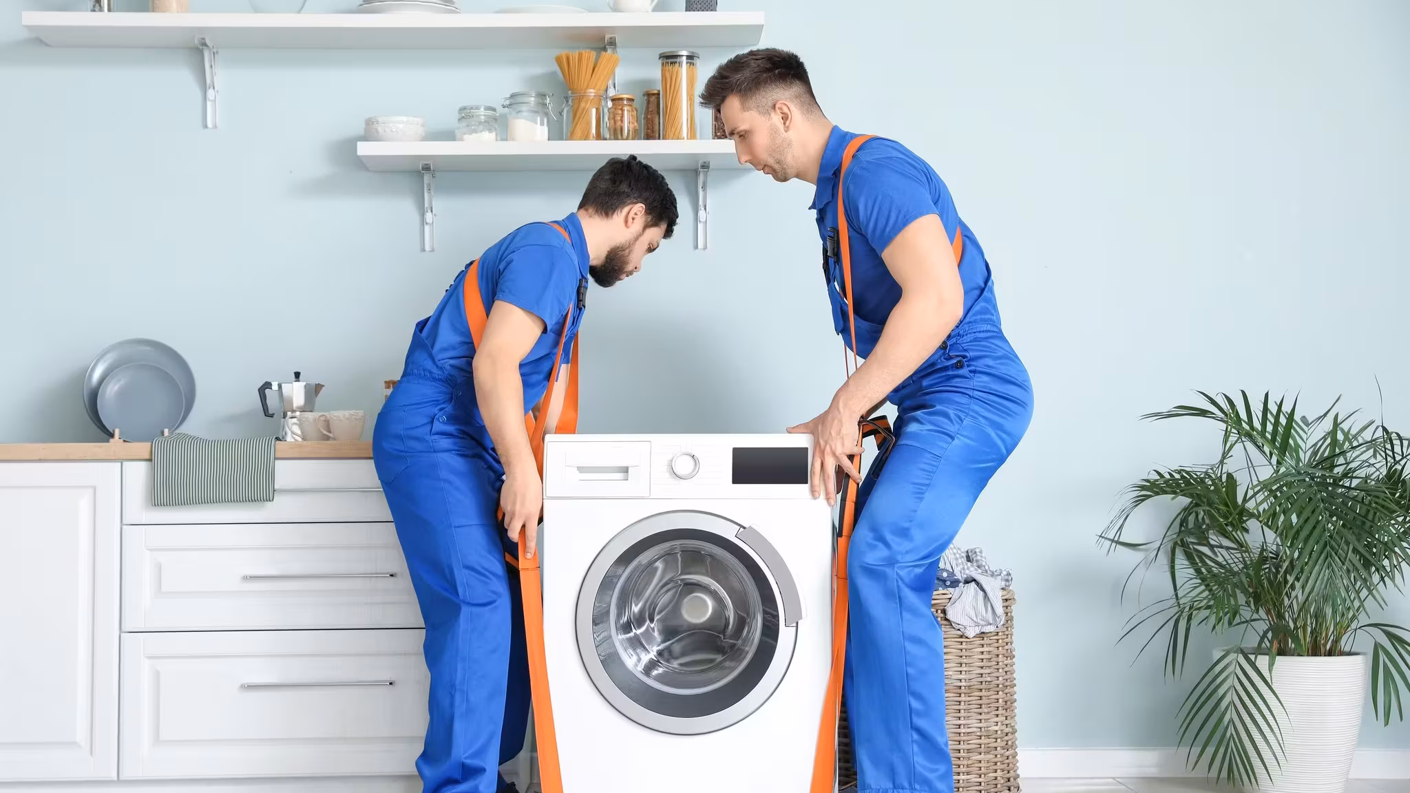 Two movers lifting a washing machine on carrying straps