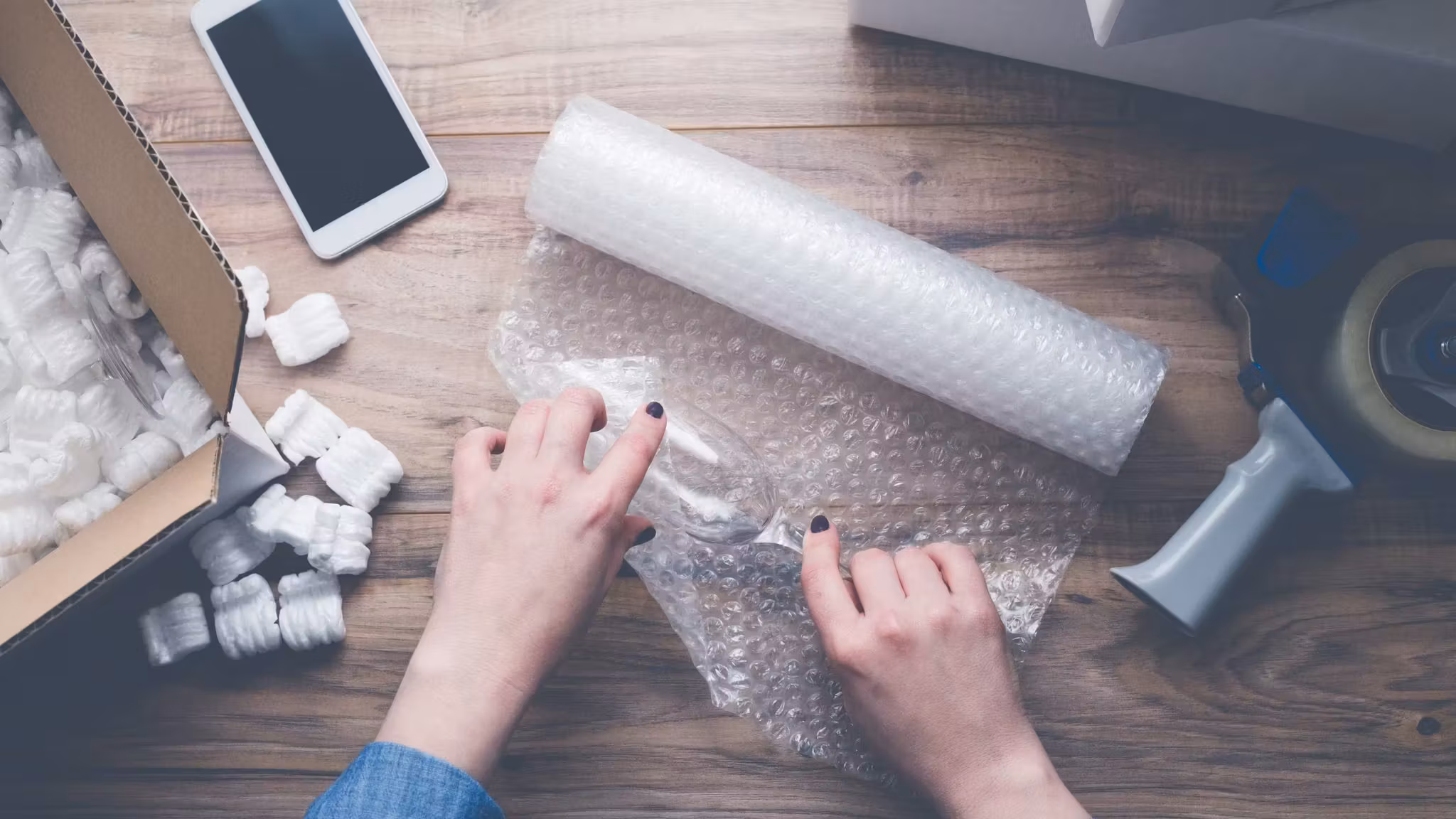 Hands unrolling stretch film beside foam corner protectors