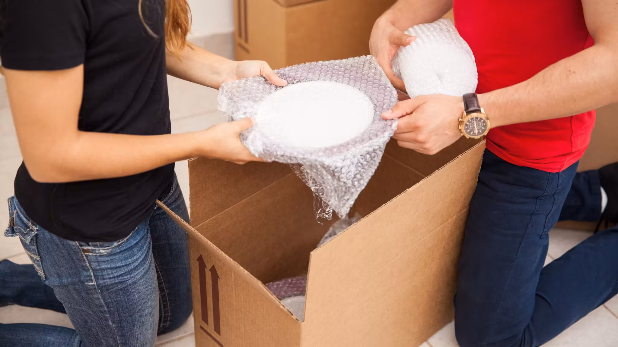 A bowl being wrapped in paper before it goes into the carton