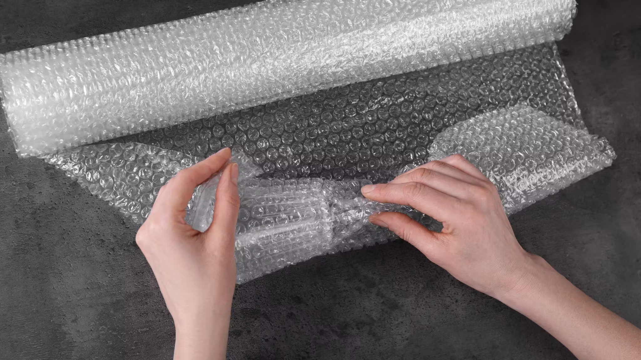 Hands smoothing a sheet of bubble wrap flat