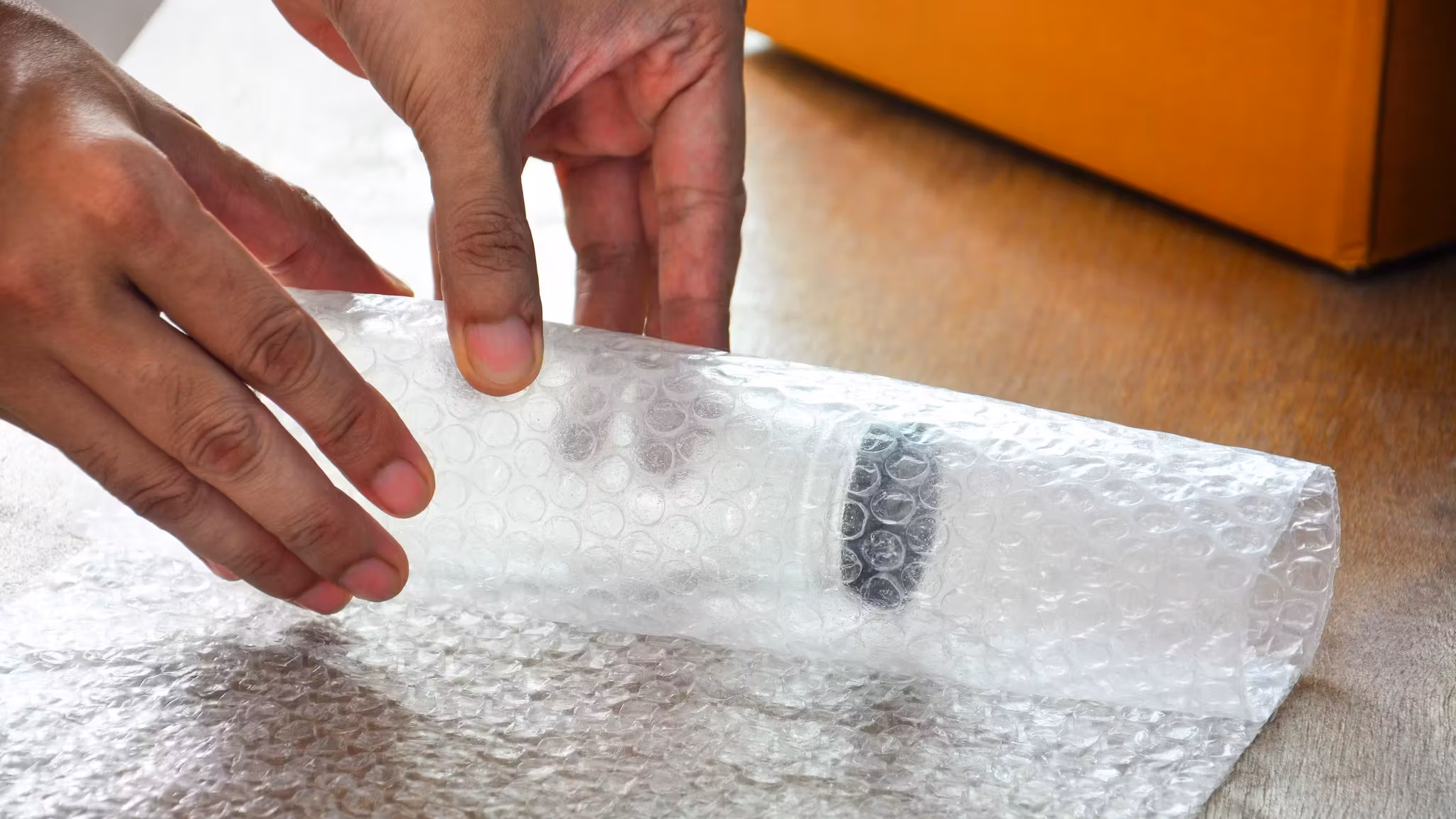 Hands tearing a strip from a roll of bubble wrap