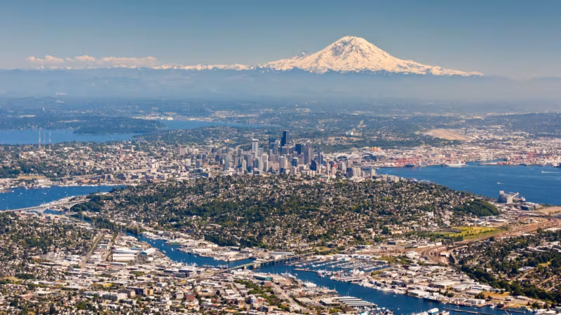 Aerial view of Seattle between its waterways, with Mount Rainier on the horizon