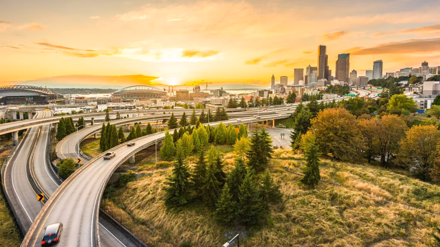 A freeway curving toward the downtown Seattle skyline at sunrise
