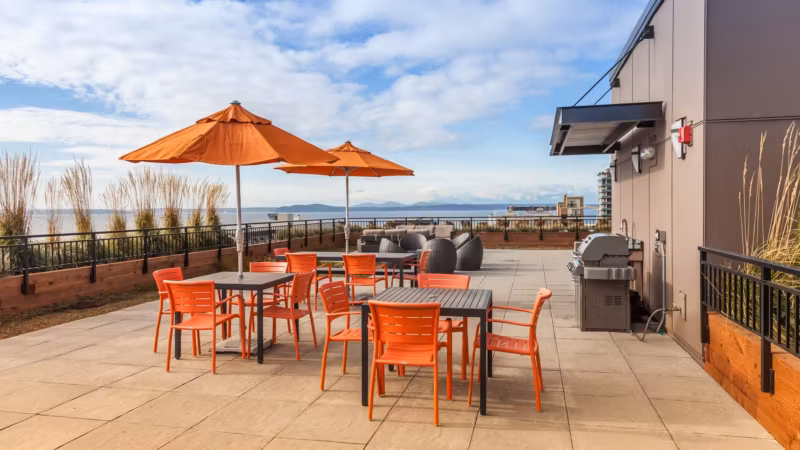 A rooftop terrace with tables and umbrellas overlooking the water in Seattle