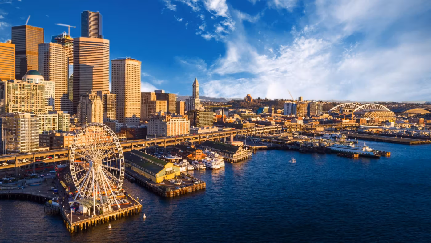 Seattle's waterfront piers and the Great Wheel lit at dusk below downtown