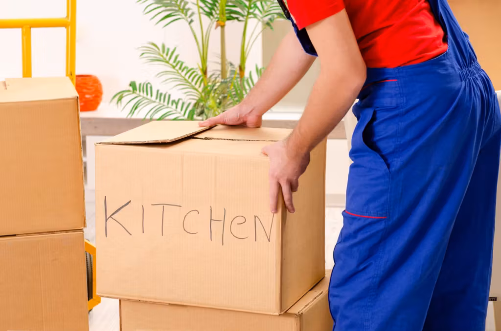 A mover setting down a carton hand-labeled KITCHEN