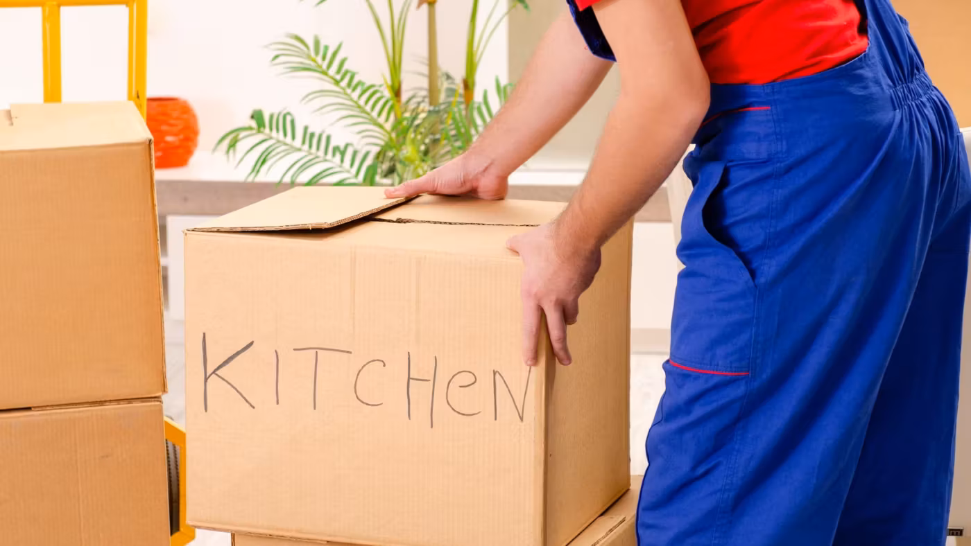 A mover setting down a carton hand-labeled KITCHEN