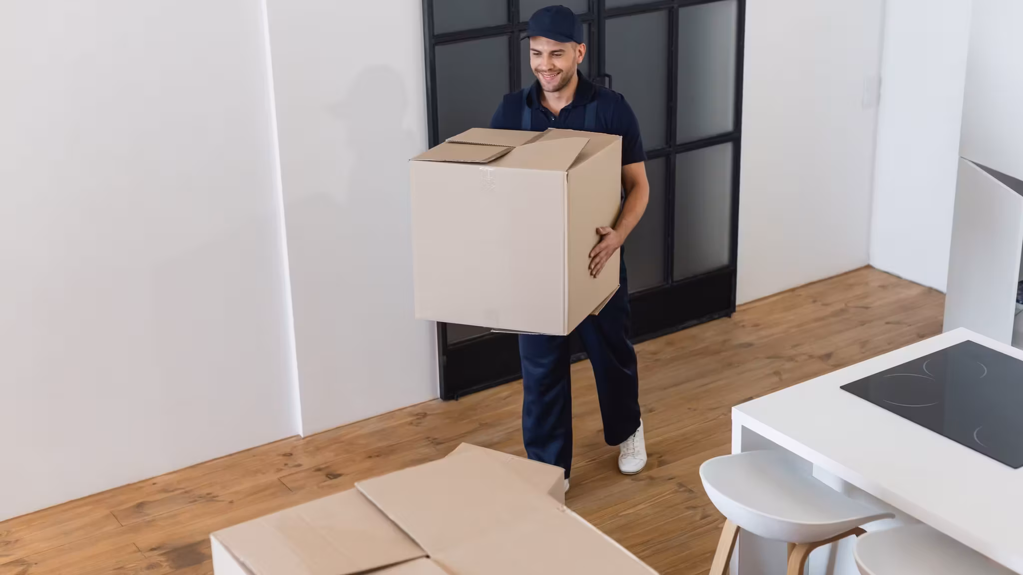 A mover carrying a carton through a doorway into a kitchen