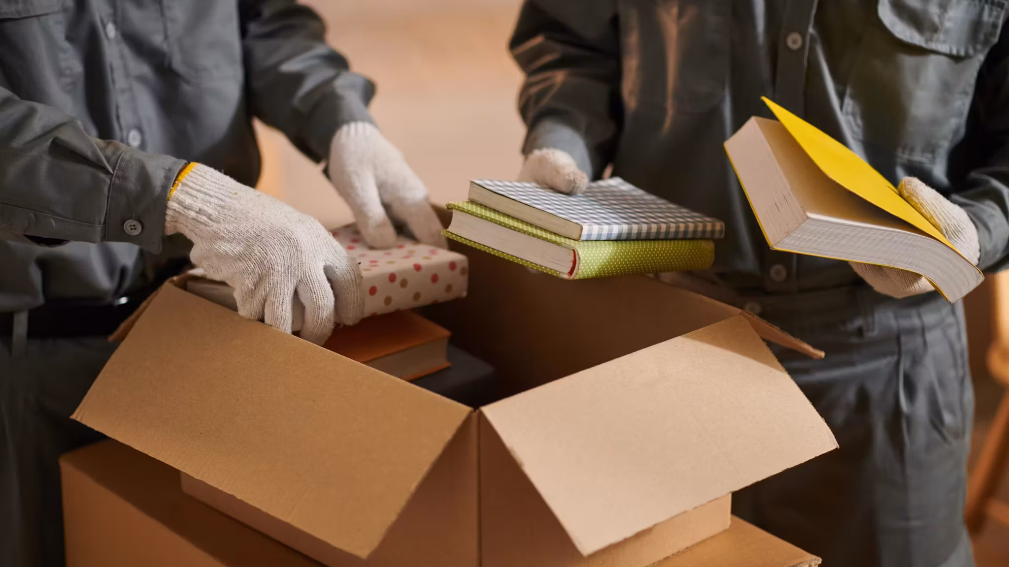 Gloved hands laying books into an open carton