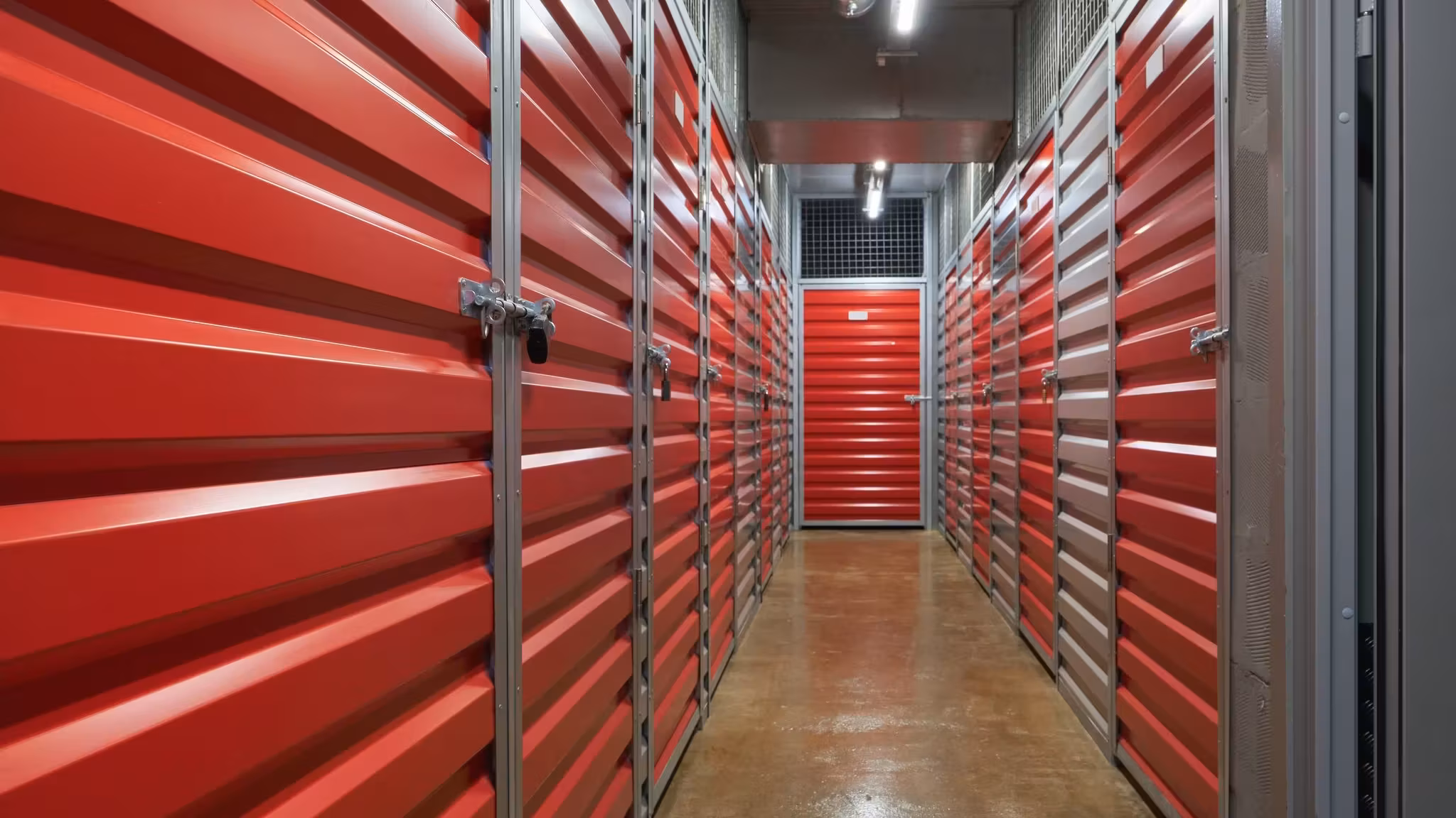 A corridor of closed red unit doors receding to the far end of the building