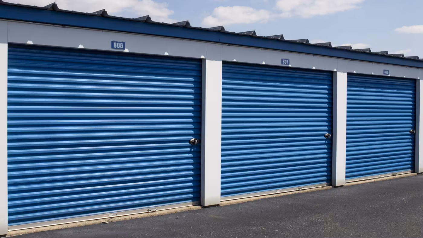 Three numbered blue roll-up doors in a row under an overcast sky
