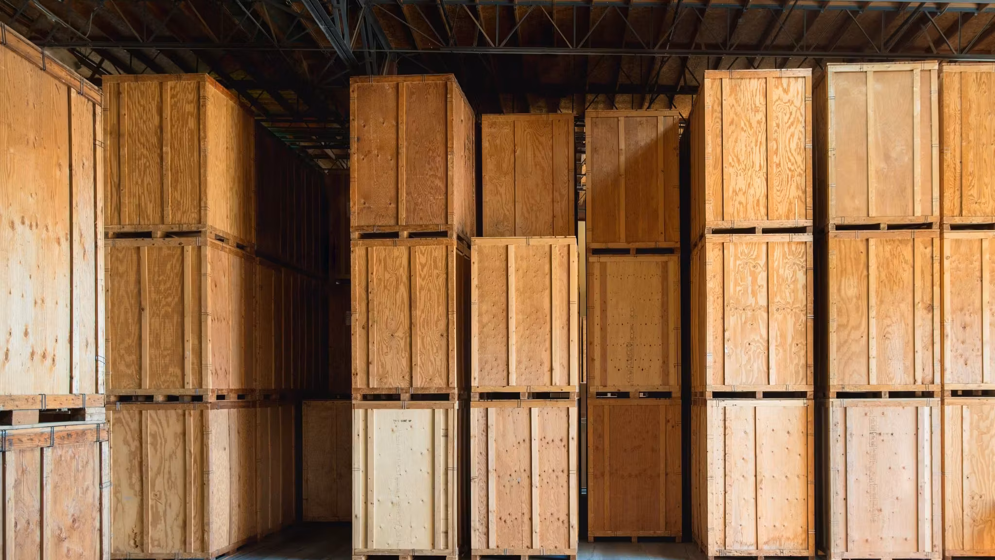 An aisle of tall plywood storage vaults stacked two high inside a warehouse