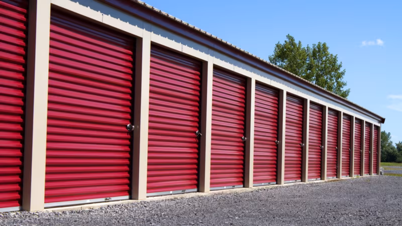 A row of red roller doors along an outdoor self-storage building