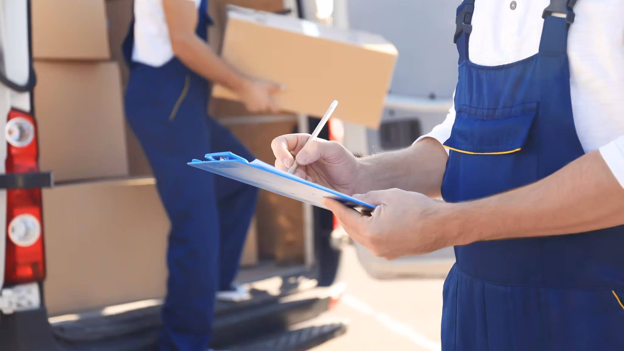 A mover in uniform writing on a clipboard