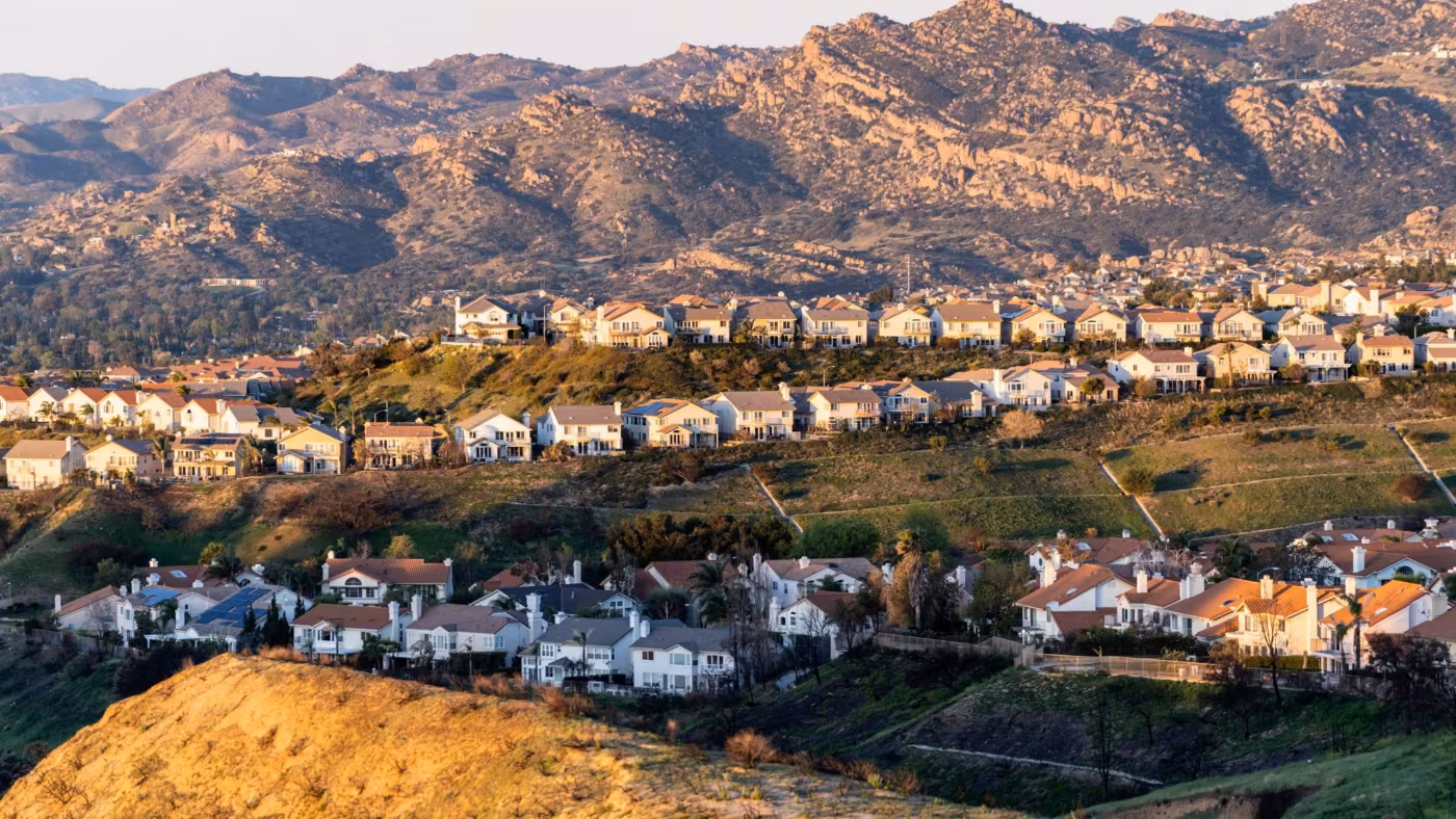 A hillside of pale houses above dry Southern California scrub