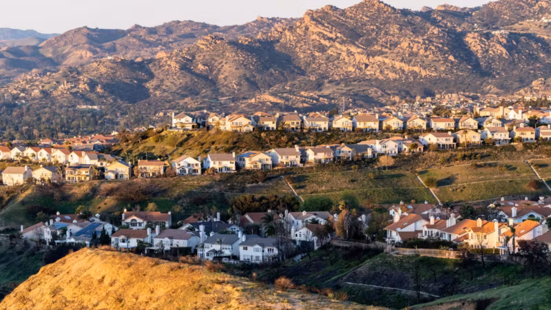 A hillside of pale houses above dry Southern California scrub