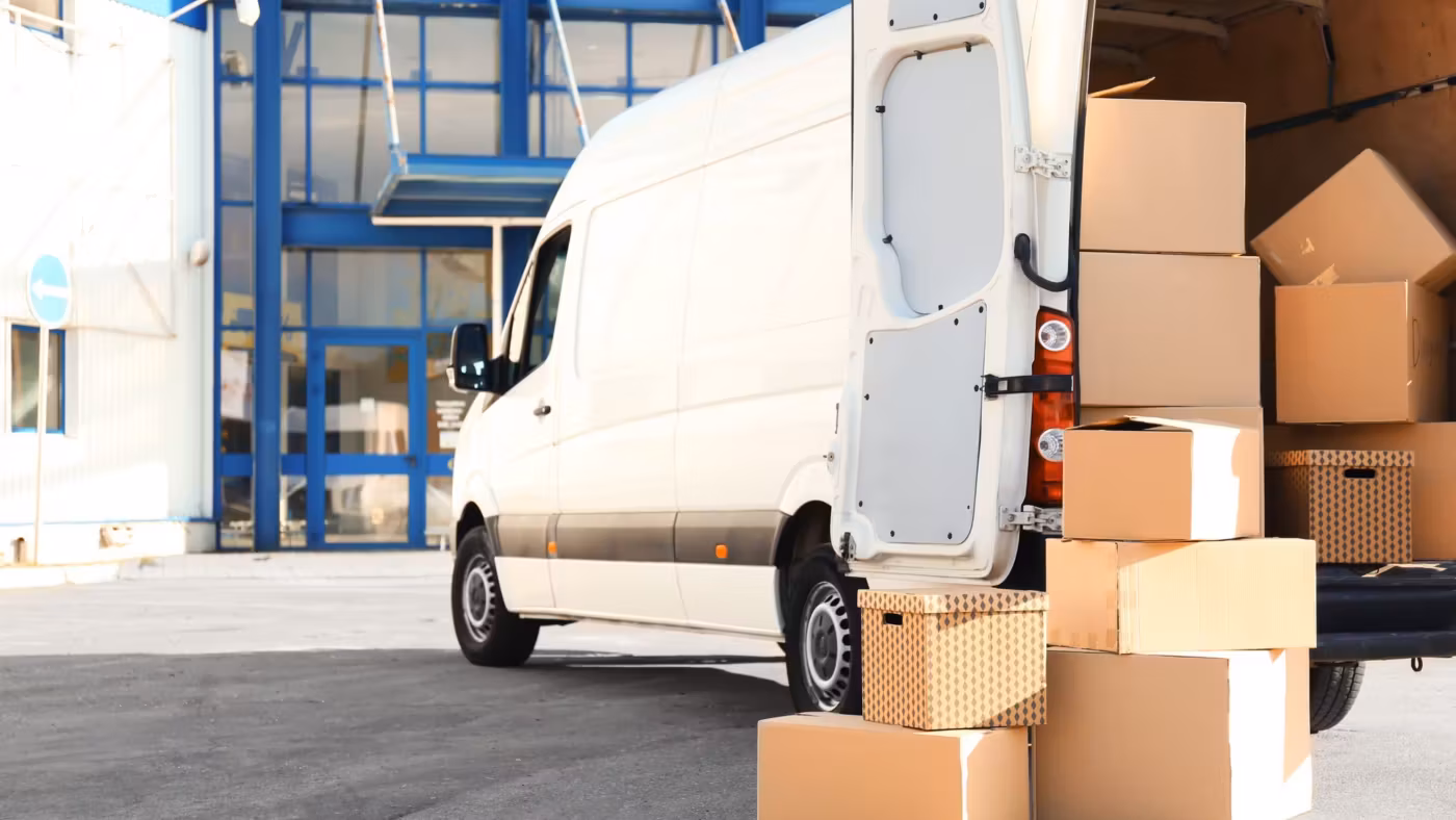A van standing open beside stacked cartons at a loading bay