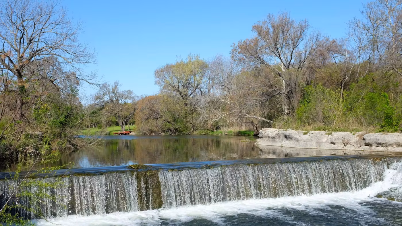 A low weir on a Texas river between wooded banks