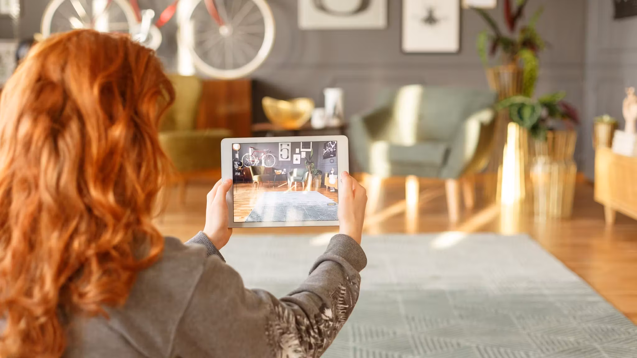 A woman photographing her living room on a tablet, furniture and framed pictures in view
