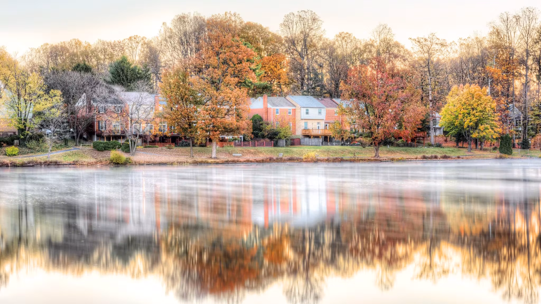 Houses among autumn trees reflected in a still Virginia lake