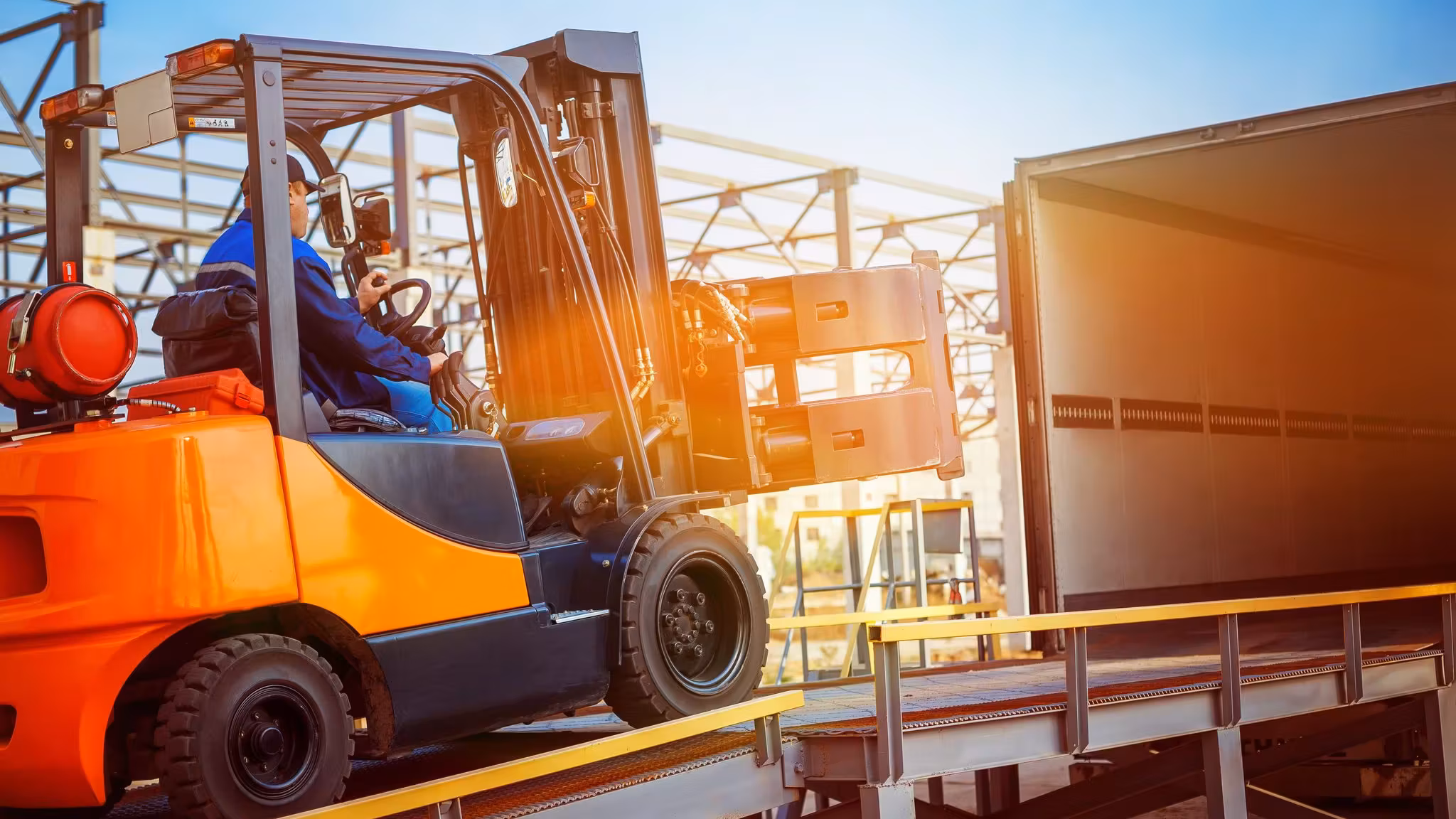 A forklift loading a pallet into a trailer at a dock