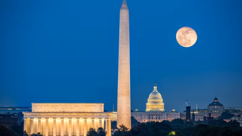 The Lincoln Memorial, Washington Monument and Capitol lit at night under a full moon