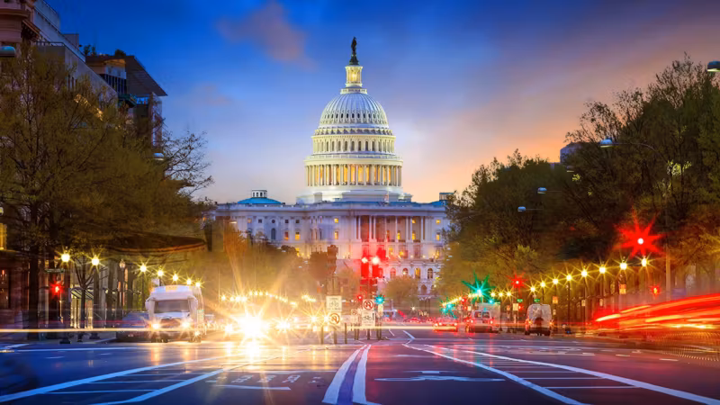 Pennsylvania Avenue at dusk with traffic light trails and the Capitol dome beyond
