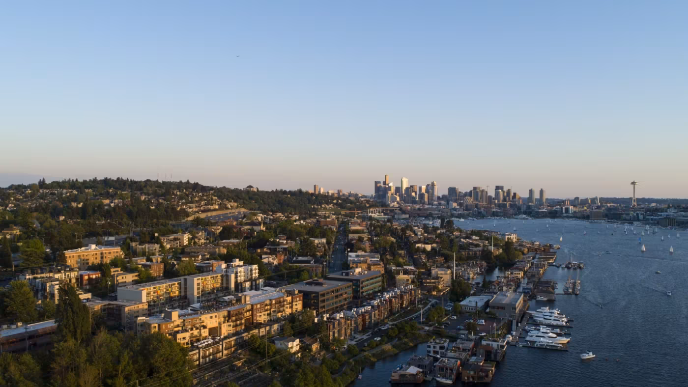 A waterfront neighborhood of low apartment blocks and marinas with Seattle beyond